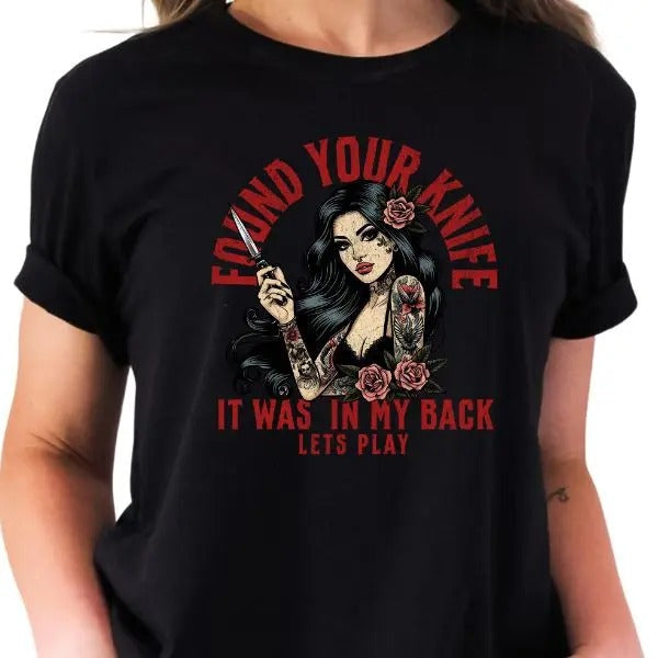 Bold Tatted Woman Holding Kn1fe T-Shirt - 'I Found Your Kn1fe, It Was in My Back' - Edgy Graphic Tee for Strong Women, Tattoo Art Statement Shirt, Unique Revenge Theme Apparel, Fierce Fashion, Standout Design, High-Quality Cotton, Perfect Gift Idea